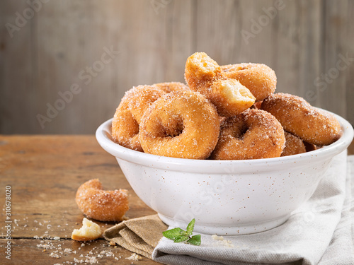 Slika na platnu Closeup of a pile of homemade rosquillas, traditional homemade anise donuts from Spain, typically eaten in Easter, on a rustic wooden table, copy space