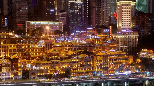 Timelapse famous orange illuminated Chungking ancient Northwest Gate against city buildings with flashing advertisement at night in southwest China