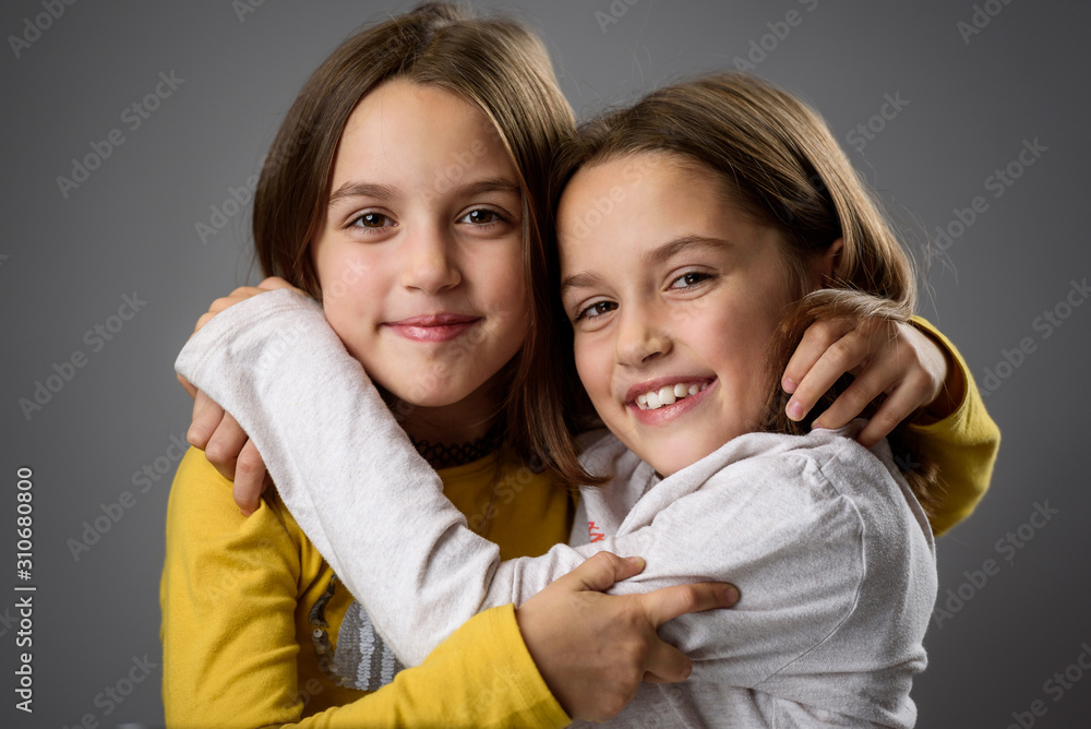 Identical twin girls sisters are posing for the camera. Identical twin girls sisters are posing for the camera.
