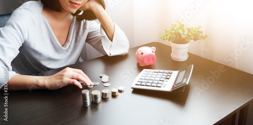 Asian women counting coins and pressing the calculator to calculate the money received from the piggy bank for something with happiness and contentment. Maybe saving to buy house, car, gift for lover