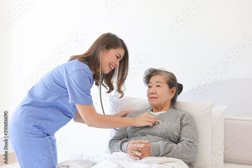 Asian Senior old woman on the bed with doctor and her son in hospital