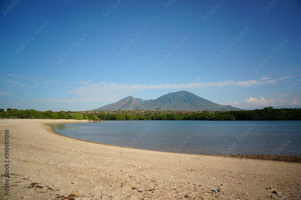 the atmosphere of the beach or the coast before the afternoon with calm waves and sunny weather set against the background of the high seas and mountains or plateaus