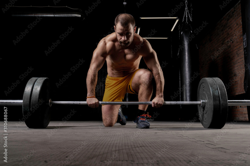 Strong weightlifter with muscular body prepares to lift the barbell Strong weightlifter with muscular body prepares to lift the barbell