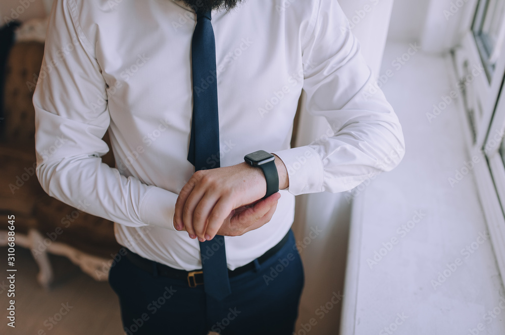 Male businessman holds hands for a smartwatch. Business. The morning of the groom. A young guy looks at his watch and is going to work. Modern technology. Photography, concept. Male businessman holds hands for a smartwatch. Business. The morning of the groom. A young guy looks at his watch and is going to work. Modern technology. Photography, concept.