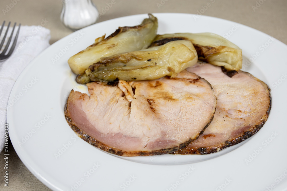 roast pork and braised endives on a plate roast pork and braised endives on a plate