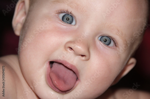 portrait of a baby with blue eyes showing tongue