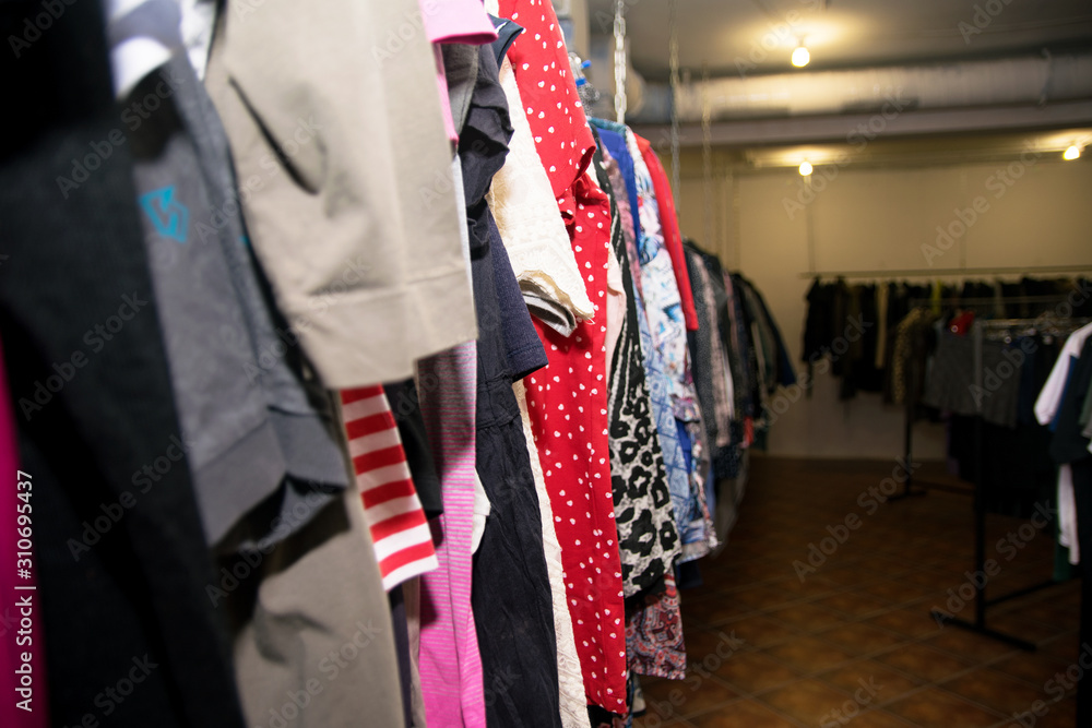 Different clothes: skirts, sweaters, dresses and jackets hang on hangers in the store