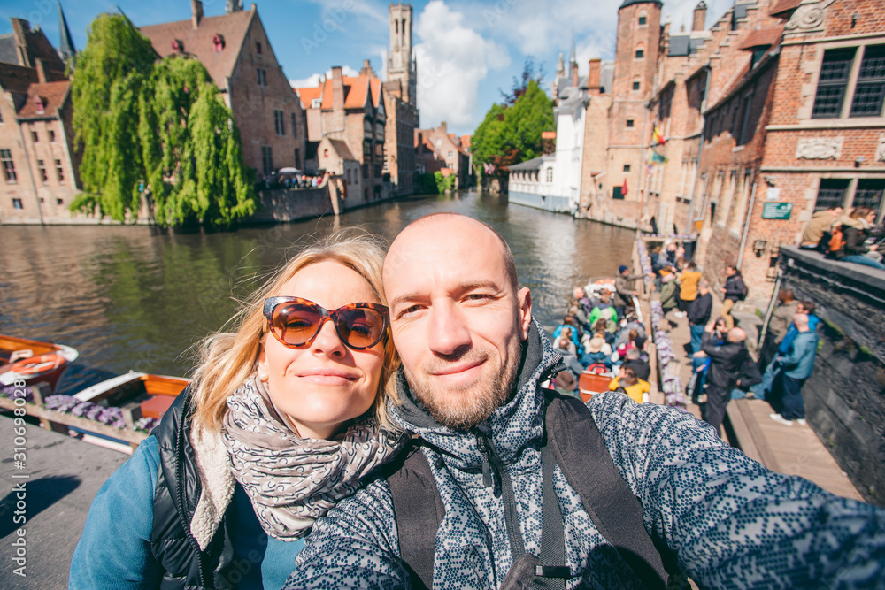 Fototapeta premium Young couple takes selfie pictures on the main street of Bruges, Belgium.