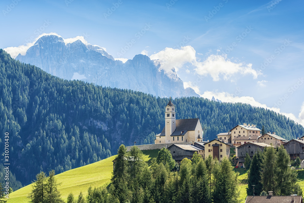 Catholic Church in a small town on the slope of a green Sunny hill in the Julian Alps, Slovenia