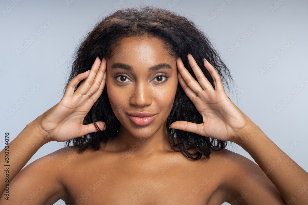 Beautiful Afro-American woman touching her face in studio