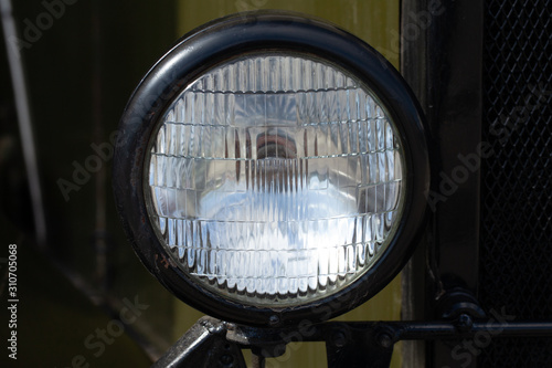 Round headlight of a military car, old-timer vehicle