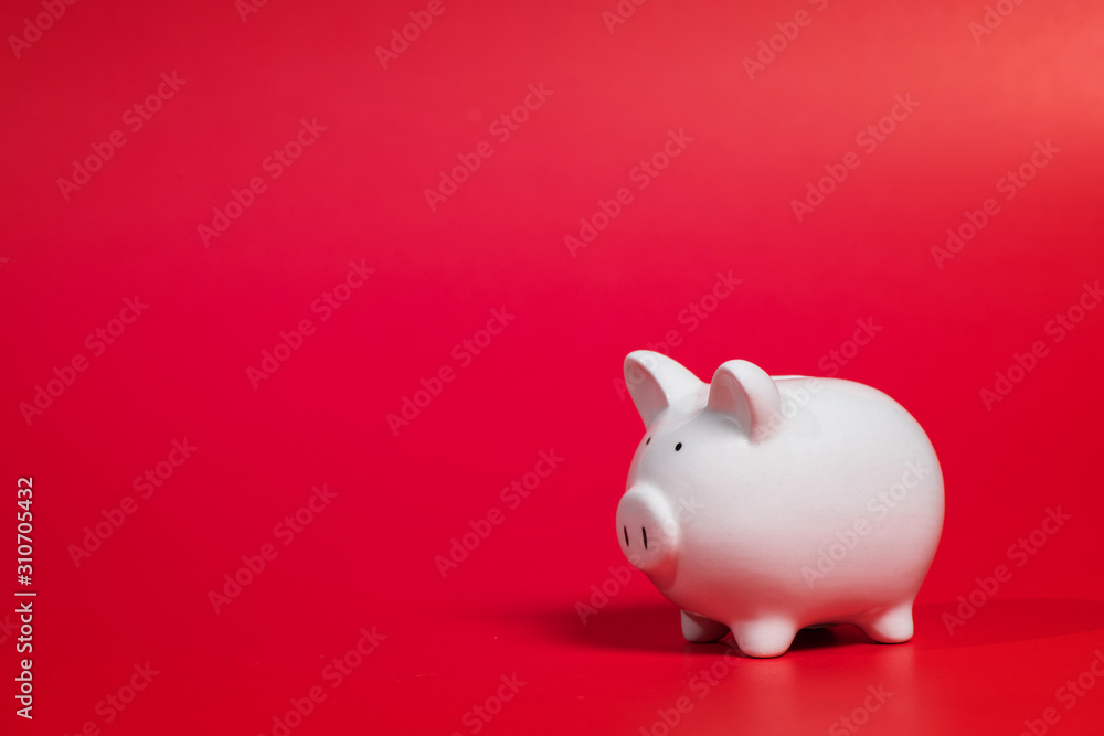 Composition with piggy bank isolated on red background.