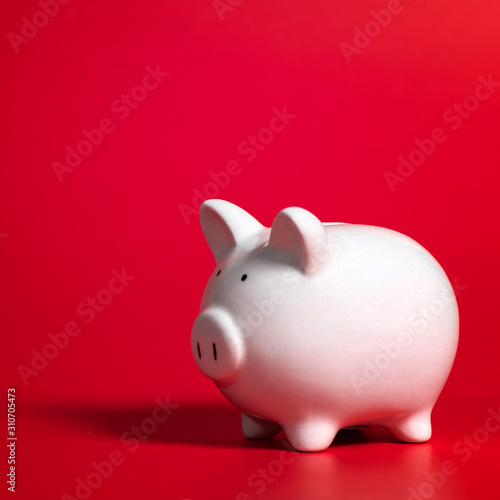Composition with piggy bank isolated on red background.