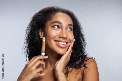 Pretty Afro American woman with curly hair keeping syringe in hand