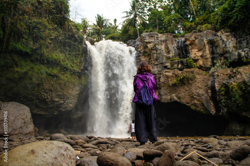 A young girl in a giant waterfall next to the village of Ubud in Bali