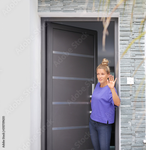 Beautiful woman opening the door of her home.Inviting the guests	