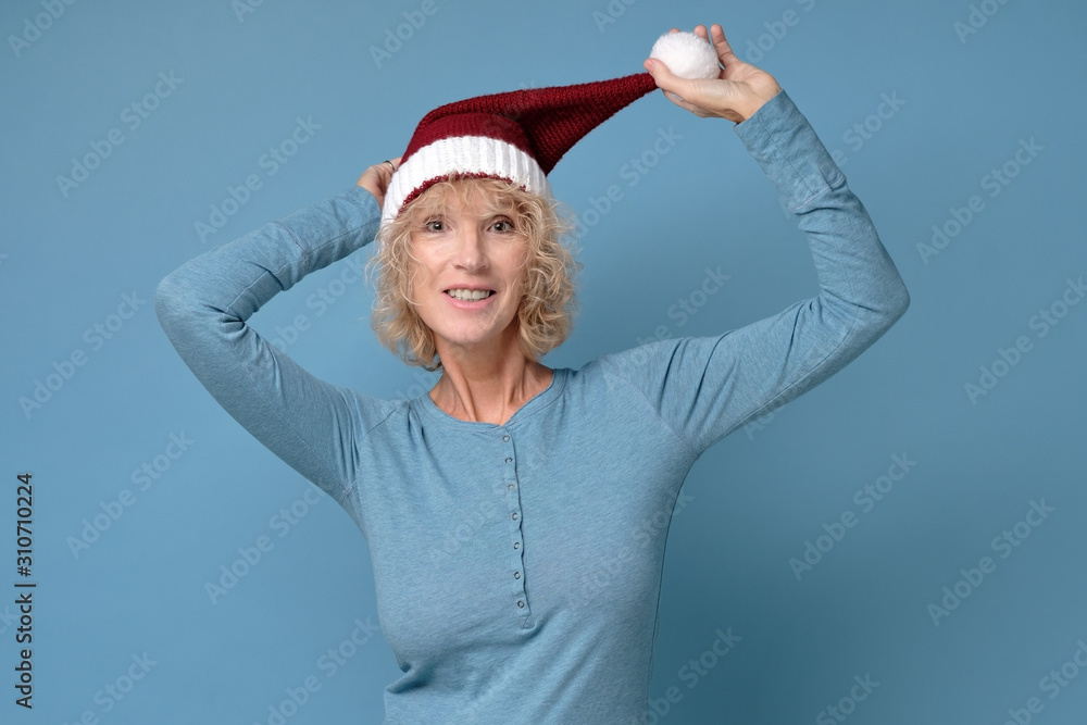 Obraz premium Pretty christmas woman in red santa hat, smiling isolated on blue background. New year concept