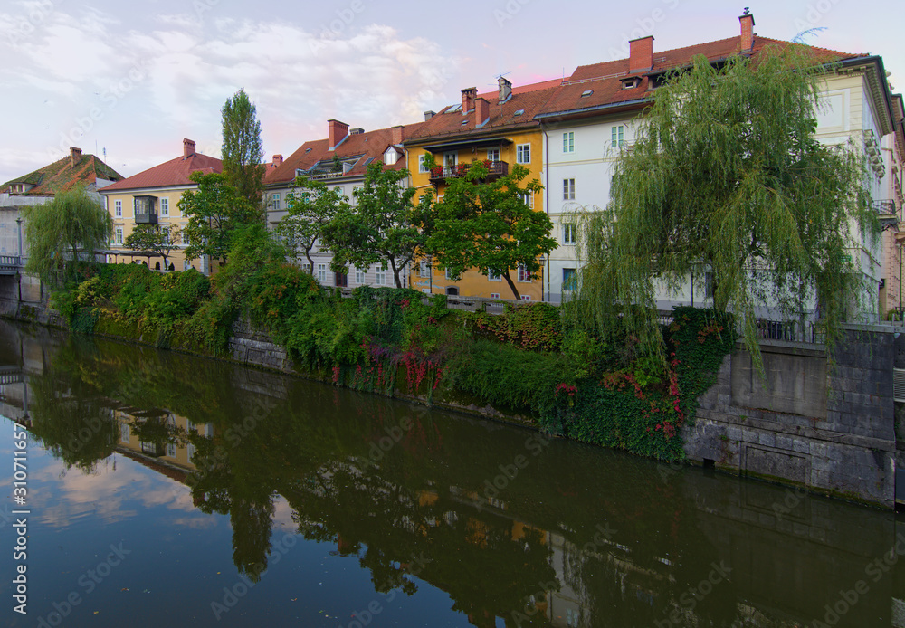 Fototapeta premium Scenic morning view of city center of Ljubljana. Ancient colorful buildings reflected in water of Ljubljanica River. Autumn landscape. Travel and tourism concept. Ljubljana, Slovenia