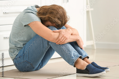 Depressed man in kitchen at...