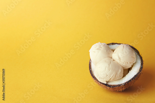 Coconut with tasty ice-cream on color background