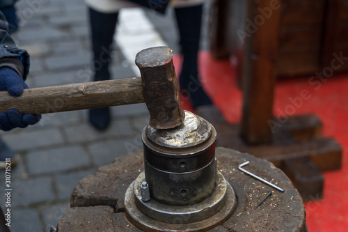Photography .minting coins at a street festival. the boy hits the anvil with a hammer