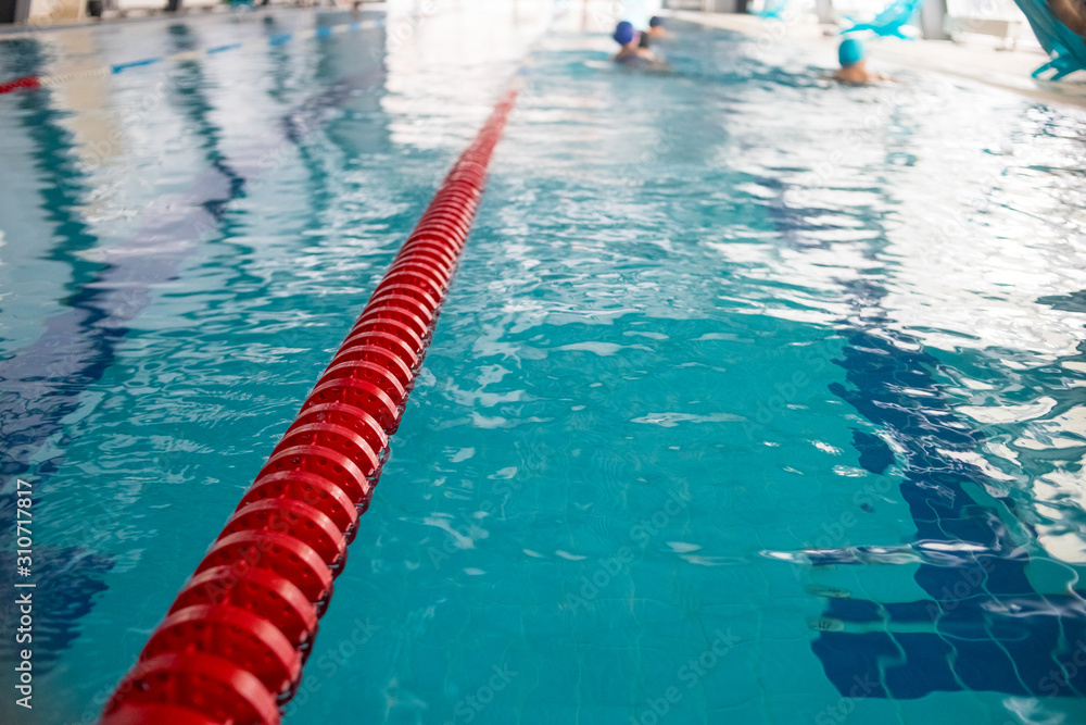 Swimming pool lanes in competition pool.red plastic rope lane on blue water indoor swimming pool sport competition background.Selective focus.