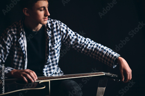 Young Boy Hold Black Guitar on Dark Background