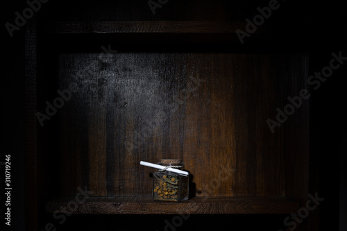 Wooden shelf with a little glass full of dried flowers