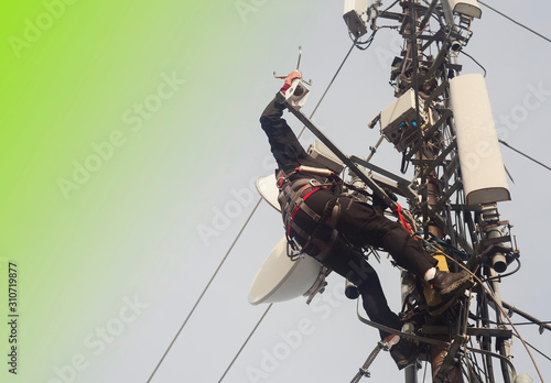 electrician man or alpinist climbing on pole antenna for inspection. abstract green background for your text