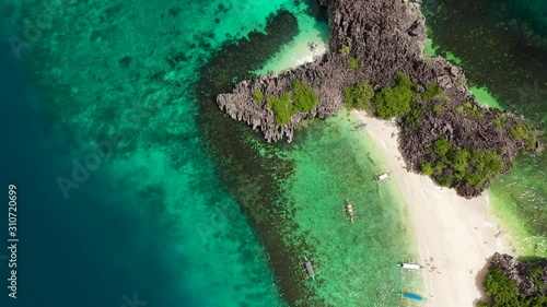 Sandy beach with tourists and tropical island by atoll with coral reef, top view. Lahos Island, Caramoan Islands, Philippines. Summer and travel vacation concept. photo