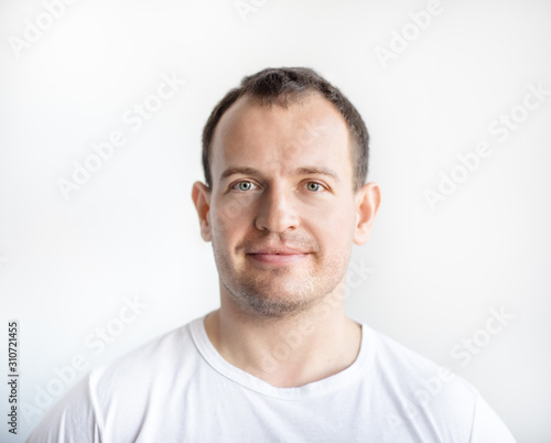 Closeup portrait of serious 30 years old caucasian white man on white background in white t-shirt. Confident happy smart modern man looking in camera. Lifestyle