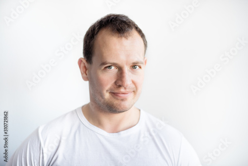 Closeup portrait of serious 30 years old caucasian white man on white background in white t-shirt. Confident happy smart modern man looking in camera. Lifestyle. Space for text