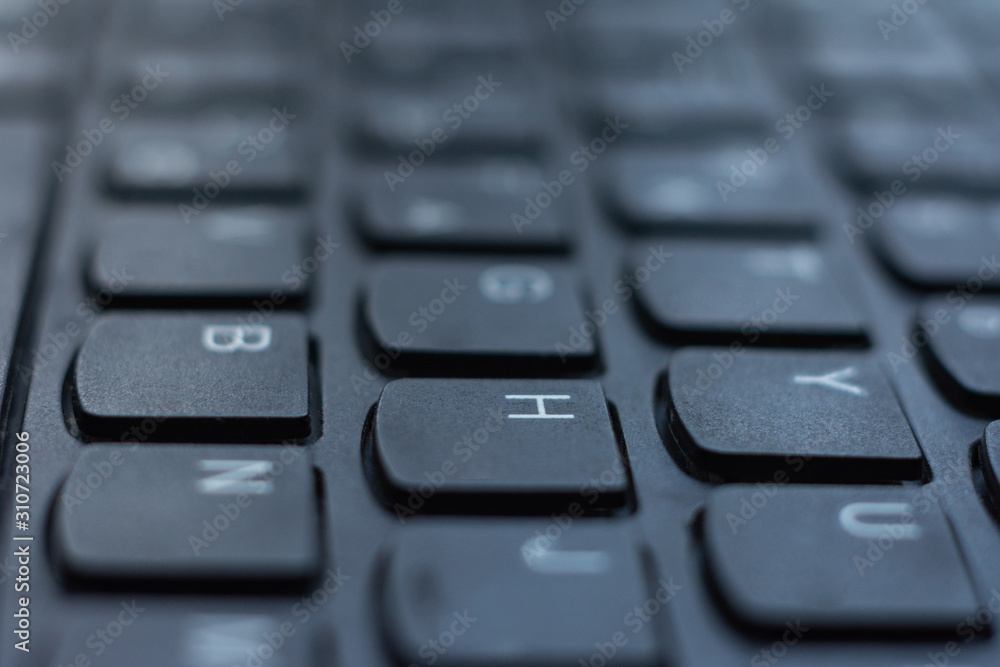 Modern black laptop keyboard closeup, english alphabet.