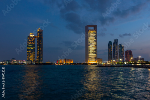Abu Dhabi skyline at night with lights reflections on the water. Shot at blue hour. 