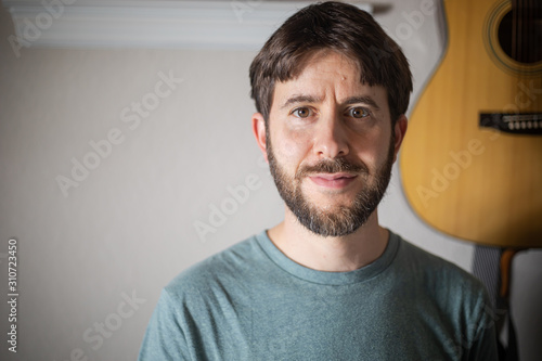 Man in front of acoustic guitar on wall