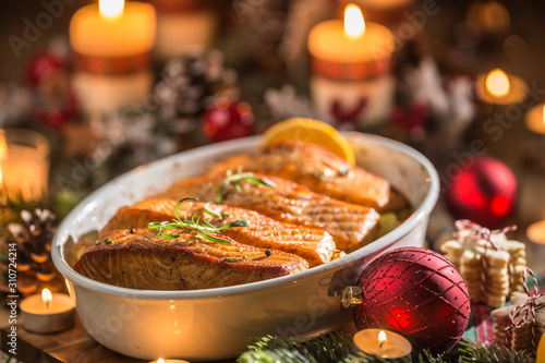 Canvas Print Christmas dinner from fish salmon in roasting dish with festive decoration advent wreath and candles