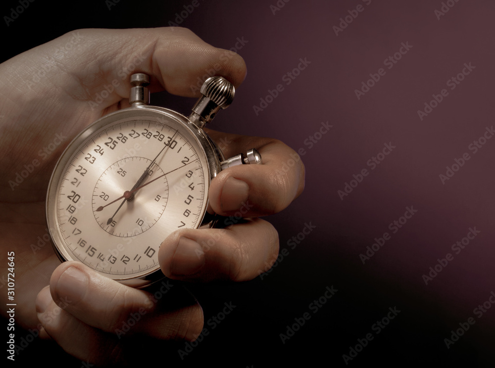 Hand Holding Stopwatch against a black background Close Up Hand Holding Stopwatch against a black background Close Up