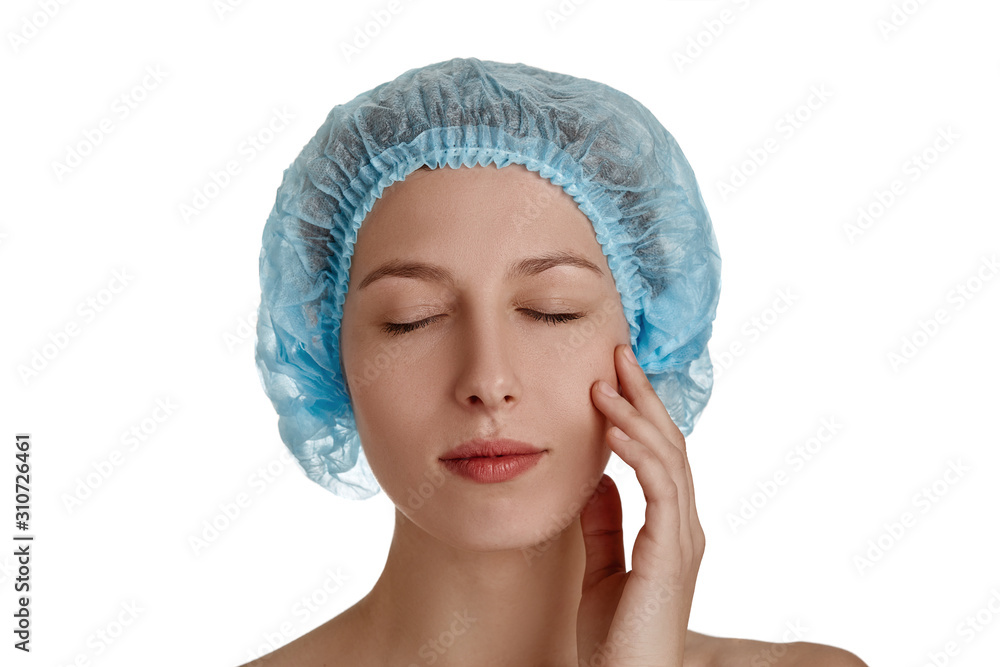 Beautiful girl in a medical cap of blue on a white isolated background. Beautiful young woman with clean fresh skin. Facial treatment. Cosmetology, beauty and spa. Skin care, close-up of the face