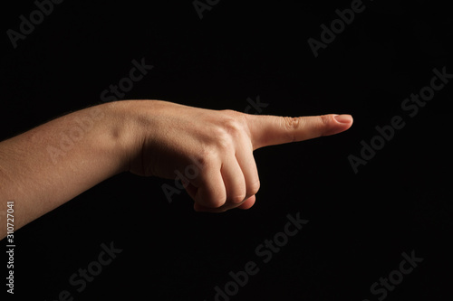 Woman hand pointing to something by forefinger, isolated on black background. Gesture of choice. Side view.