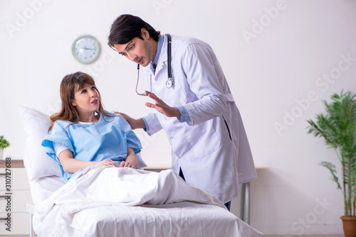 Male doctor visiting female patient in ward