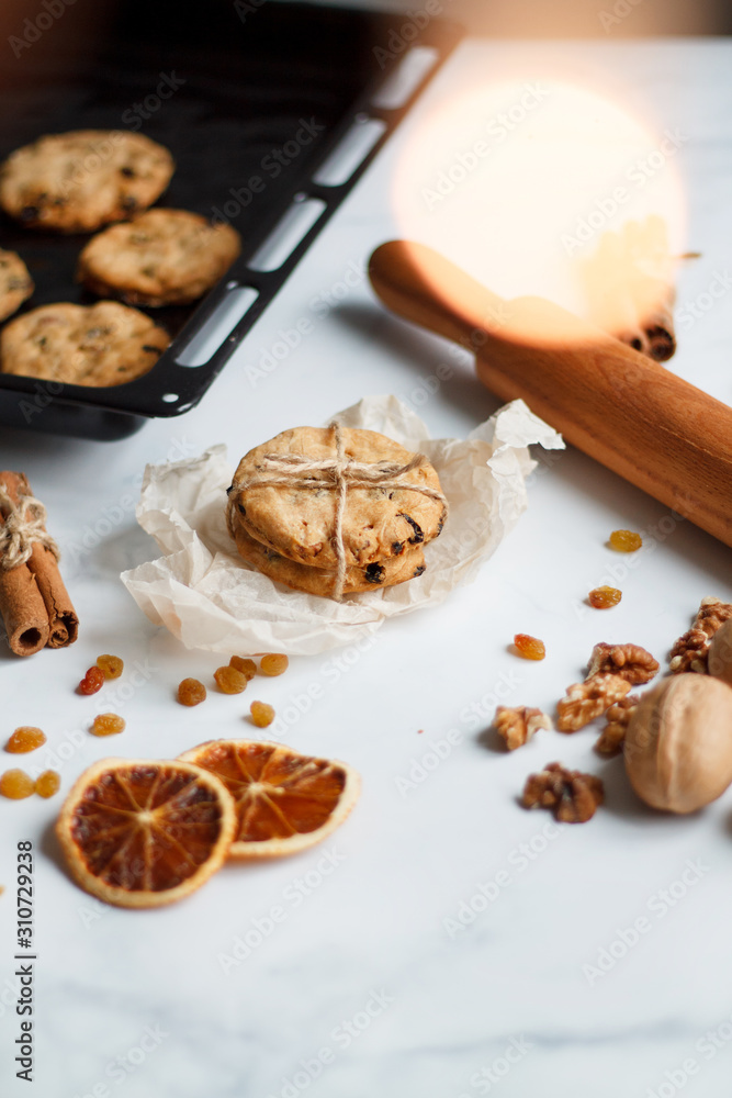 Fototapeta premium Christmas composition. cookies tied, rolling pin, cinnamon, cookies and dried orange, nuts, raisins.