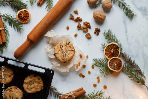 Christmas composition. cookies tied, rolling pin, cinnamon, spruce branches and dried orange, nuts, raisins. The view from the top