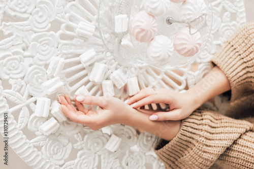 Marshmallows on the white table  pretty cozy hands on white table  top view  banner. Christmas and winter holidays