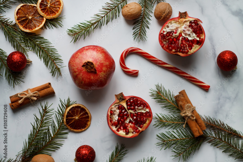 Christmas composition. red pomegranate, red cane Lollipop, cinnamon, spruce branches and dried orange. The view from the top Christmas composition. red pomegranate, red cane Lollipop, cinnamon, spruce branches and dried orange. The view from the top