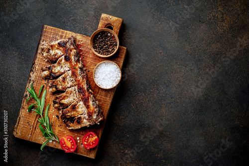  Grilled pork ribs with spices on a cutting board on a stone background with copy space for your text.