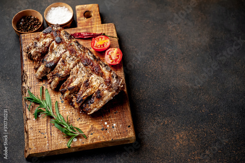  Grilled pork ribs with spices on a cutting board on a stone background with copy space for your text.