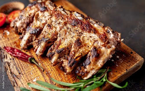 Grilled pork ribs with spices on a cutting board on a stone background 
