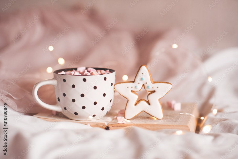 Gingerbread with cup of coffee staying on open book over glowing Christmas lights closeup. Good morning. Breakfast. Xmas. Gingerbread with cup of coffee staying on open book over glowing Christmas lights closeup. Good morning. Breakfast. Xmas.