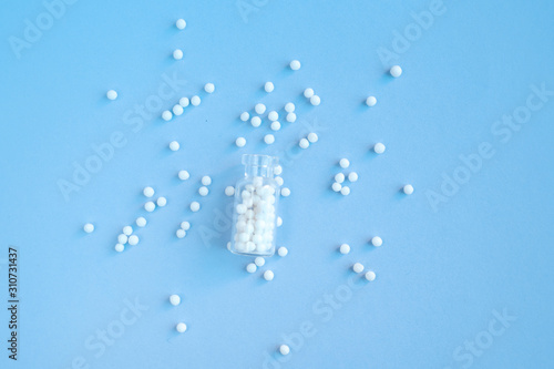 Homeopathy globules in glass bottles on a blue background. Alternative homeopathy herbal medicine, pills. Copyspace for text. photo