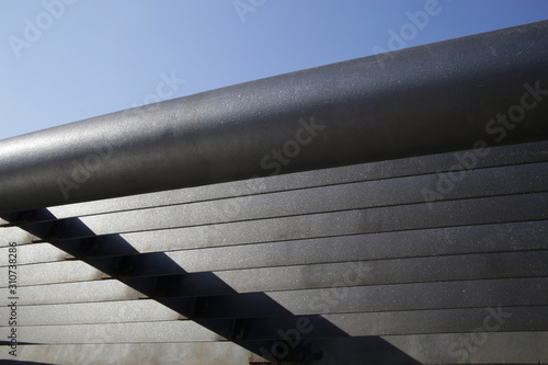 Metal girder lath structure. Detail of industrial building. Abstract modern architecture. Geometric background with parallel lines and angular shadow on linear pattern.